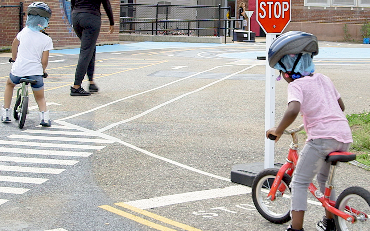 Children riding a bike, stopped at a stop sign Children riding a bike, stopped at a stop sign