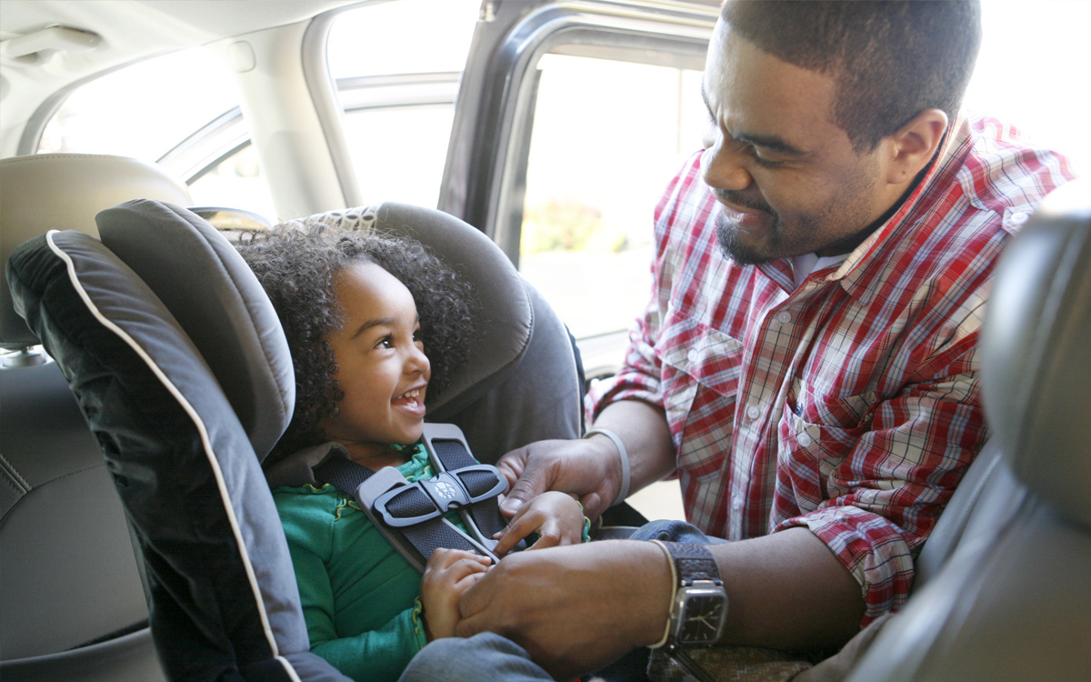 Person putting child in a car seat Person putting child in a car seat