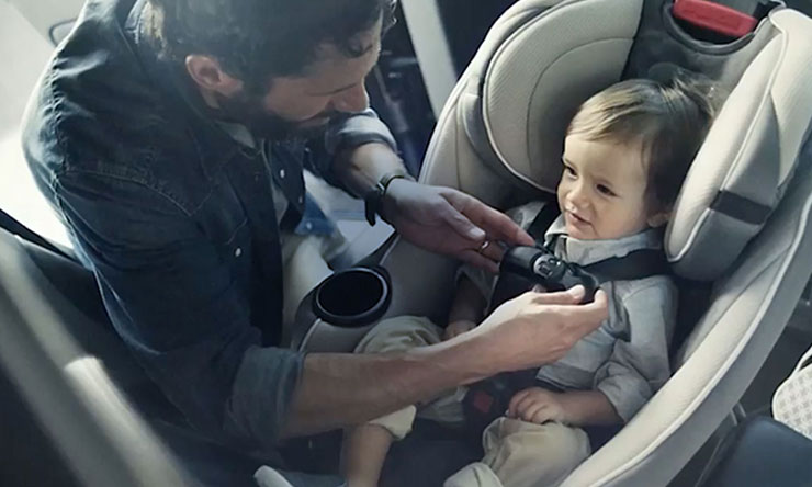 Photo of infant in being buckled into car seat by parent