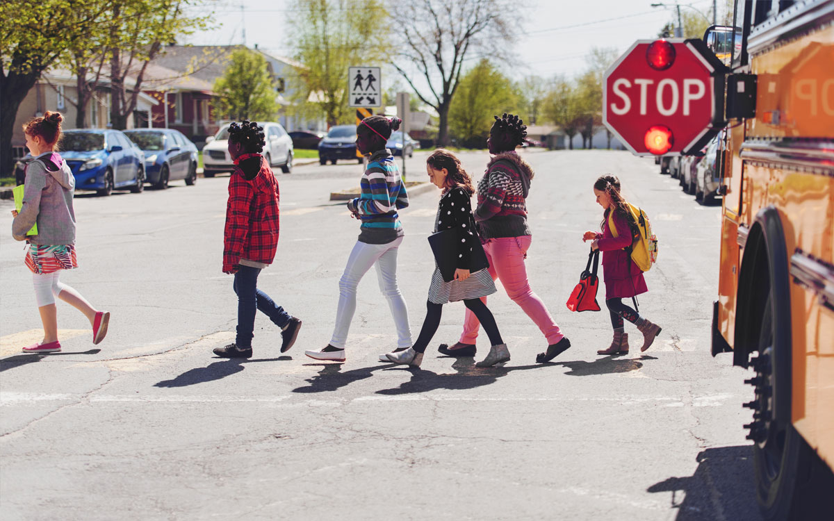 Students crossing in front of a school bus, stop sign out Students crossing in front of a school bus, stop sign out