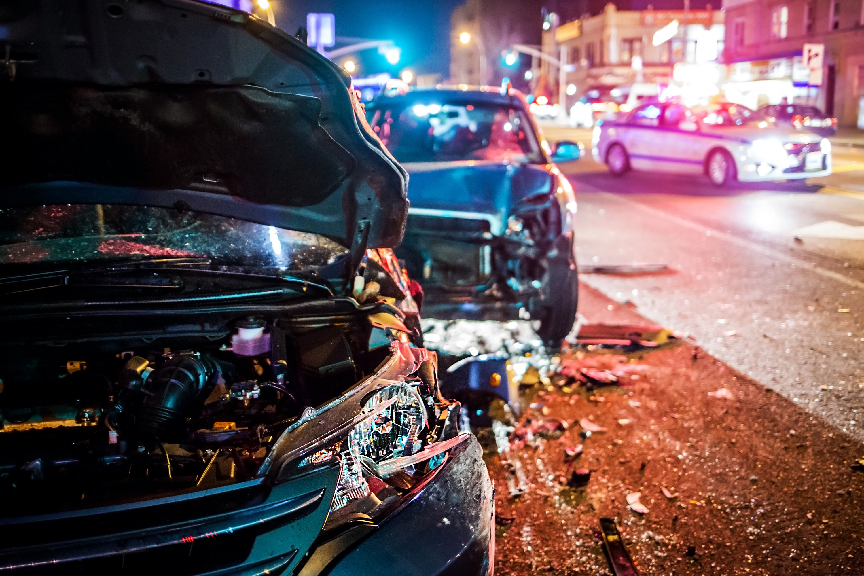 two crashed car on the road side with police cars in the background