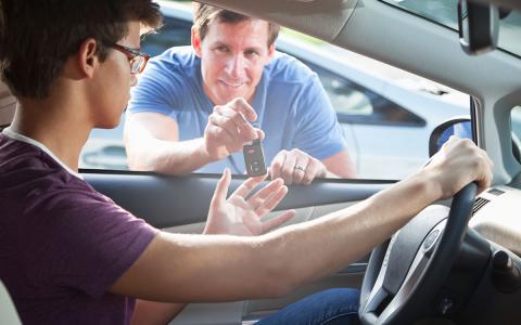 Father handing teen boy keys to car Father handing teen boy keys to car