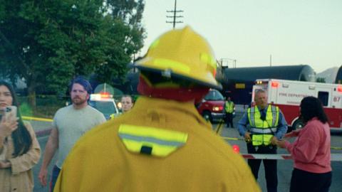 Still frame of video showing an emergency scene; fire, EMS, bystanders
