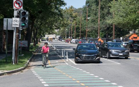 Bicyclist in a bike with car waiting to turn.