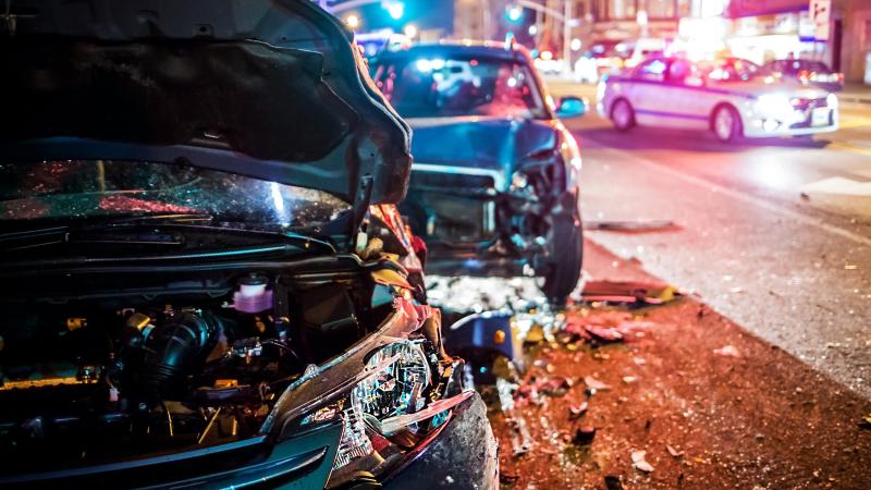 two crashed car on the road side with police cars in the background